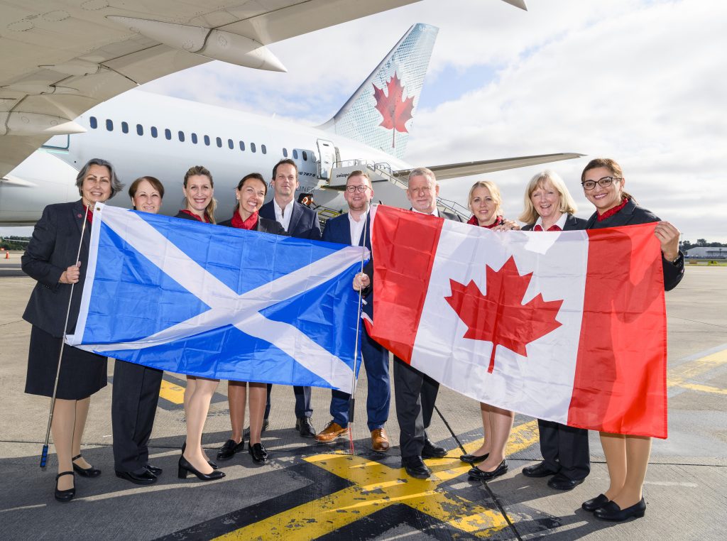 an-air-canada-airplane-flying-in-the-sky-above-clouds-and-water-with